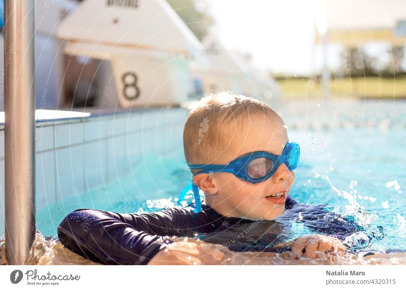Child in goggles in swimming pool blue boy vacation water outdoor child summer happy kid joy smile wet recreation play leisure sunny fun swimmer cheerful cute