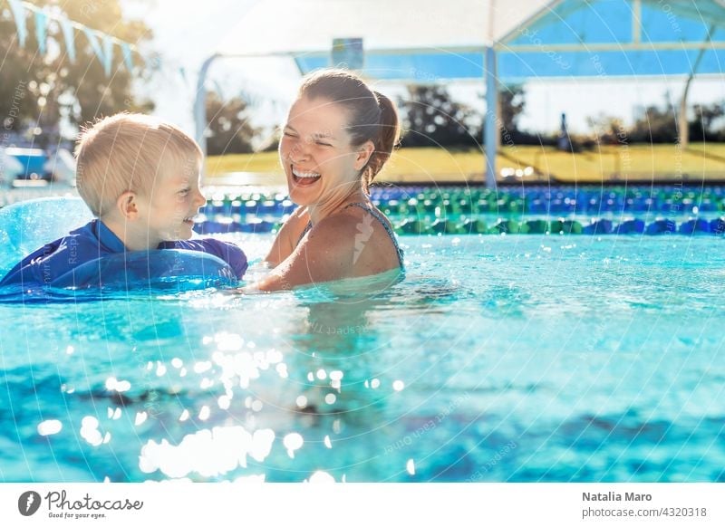 Mother and child in swimming pool woman boy mother vacation tube water outdoor summer happy blue kid joy female smile wet recreation play leisure sunny fun