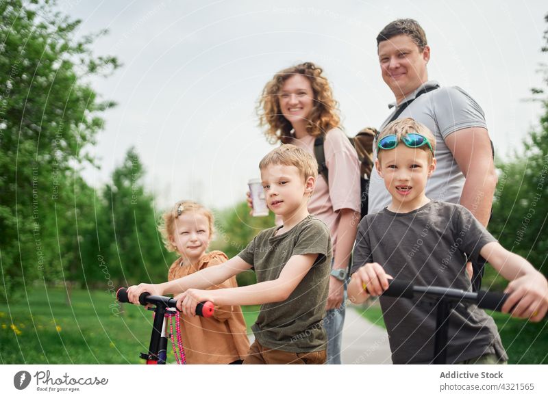 Cheerful family having fun in together in park scooter children weekend amusement entertain cheerful couple love relationship bonding happy sibling enjoy ride