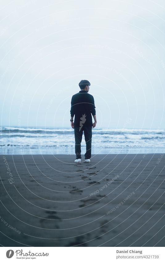 Men with his footprint on the beach Beach men Back Moody mood Exterior shot Ocean Water ocean beach Waves standing Looking young teen alone lonely one person