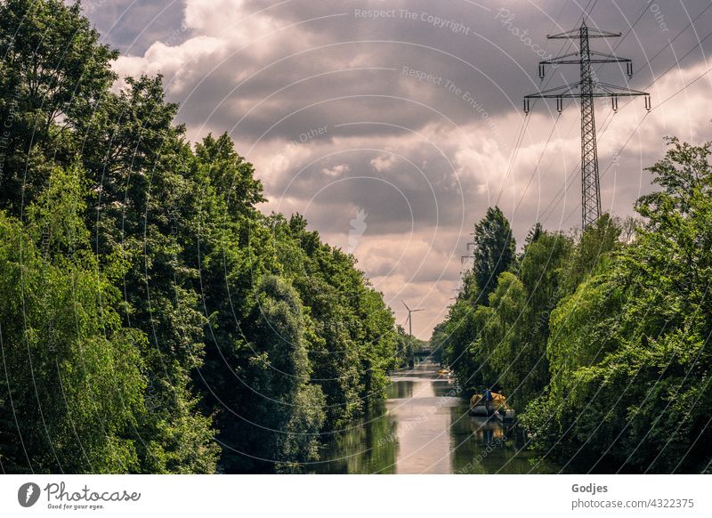 River between green trees with view of wind turbine and power pole, energy turnaround Nature Electricity Wind energy plant High voltage power line