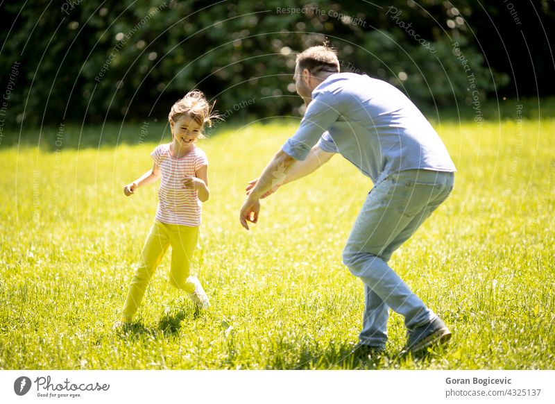 Father chasing his little daughter while playing in the park cheerful father running people outdoors family offspring dad happy parenting smiling girl child