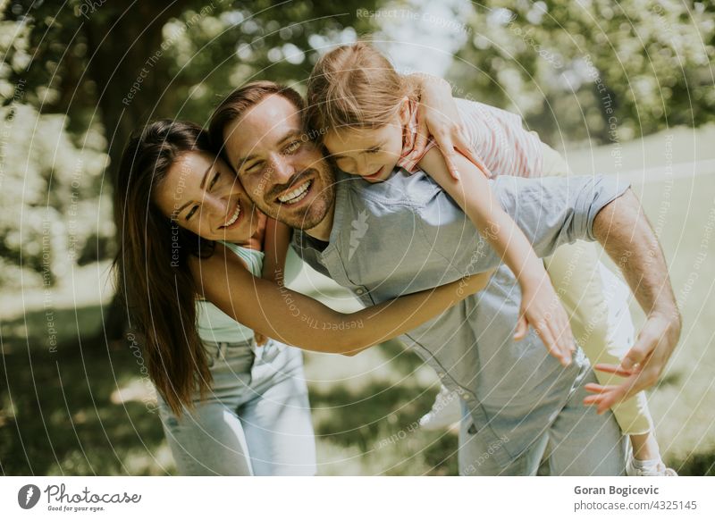 Happy young family with cute little daughter having fun in the park on a sunny day adult beautiful caucasian cheerful child childhood couple dad enjoyment