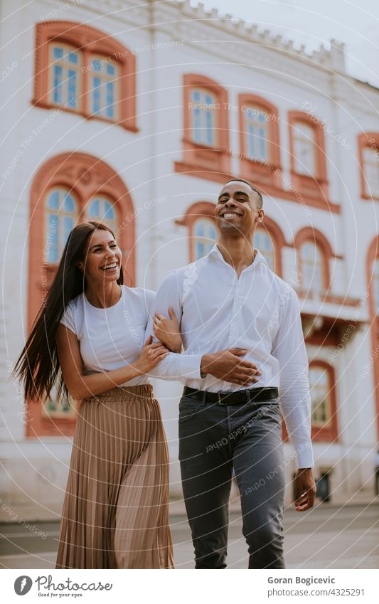 Young multiethnic couple walking on the street love woman young happy relationship together people urban romance city caucasian beautiful embracing female