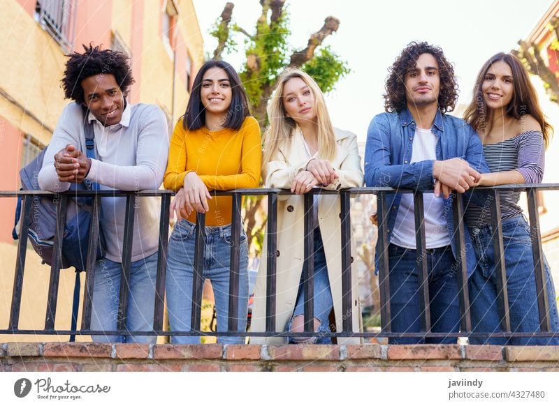 Multiracial group of young people talking together in the street. students multi-ethnic socializing diversity friends multiracial outdoors outside urban men