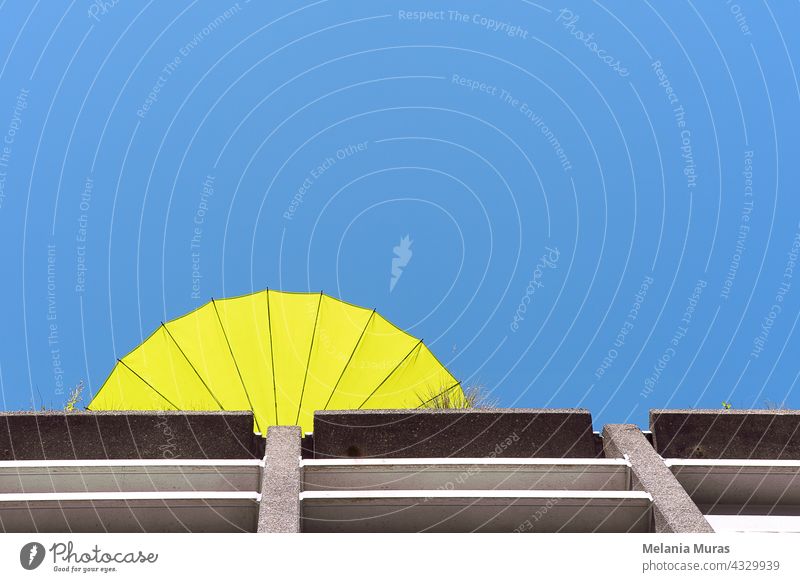 Abstract architecture, yellow sun umbrella on the roof terrace, summer vibe, bottom view. Blue sky abstract architecture abstract background beautiful blue