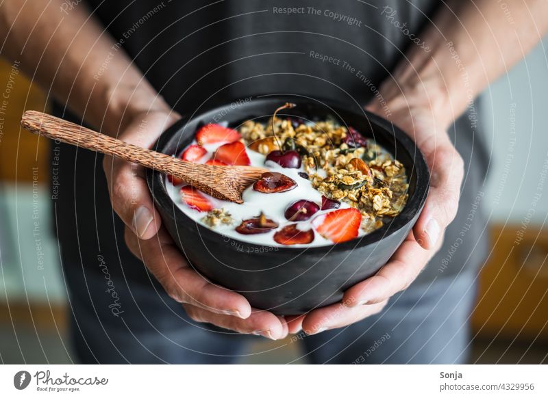 Man holds a bowl of granola, yogurt and strawberries in his hands Breakfast Yoghurt Strawberry stop subsection Cereal Healthy roasted Nut vintage Wood Diet