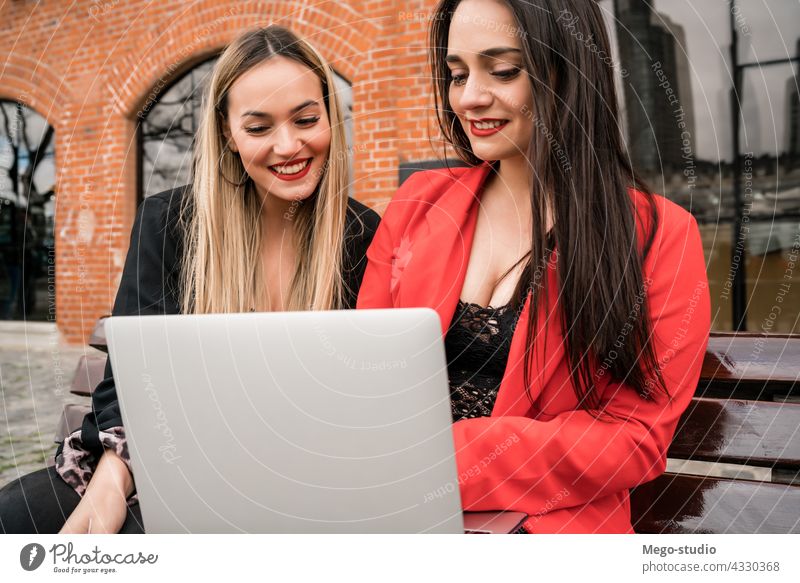 Two young friends using a laptop outdoors. two computer girl notebook leisure device joyful pc connection enjoyment two people conversation online modern