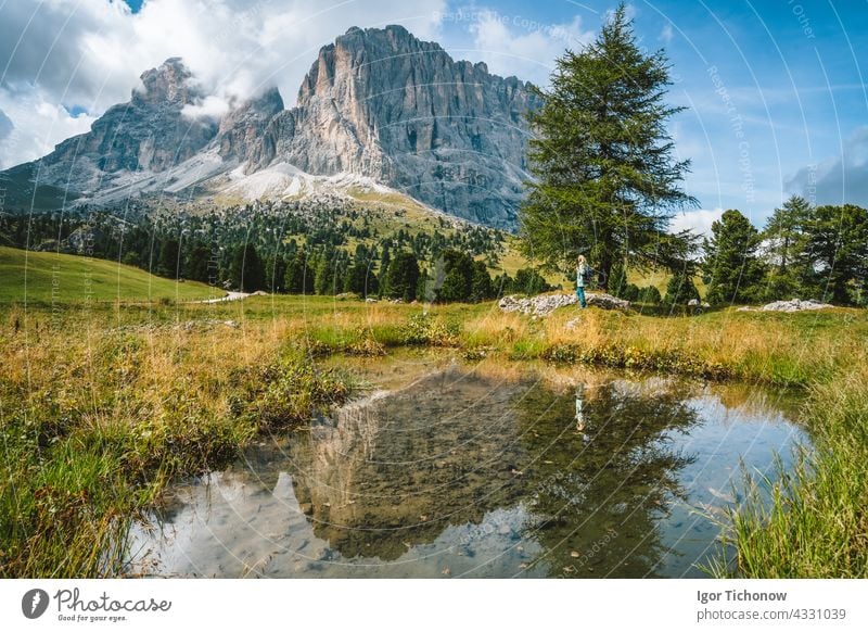 Woman hiking in Val Gardena. Pond and reflection of Sassolungo Langkofel mountain. Dolomites, Italy summer landscape dolomites woman gardena sassolungo val