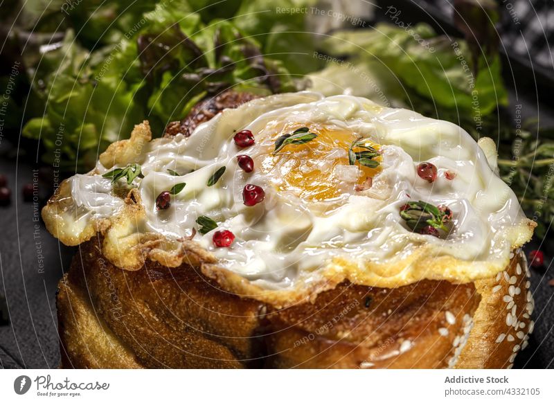 Fried egg on brioche with lettuce on black tray fried breakfast appetizing nutrition serve plate table food delicious meal dish green thyme portion palatable