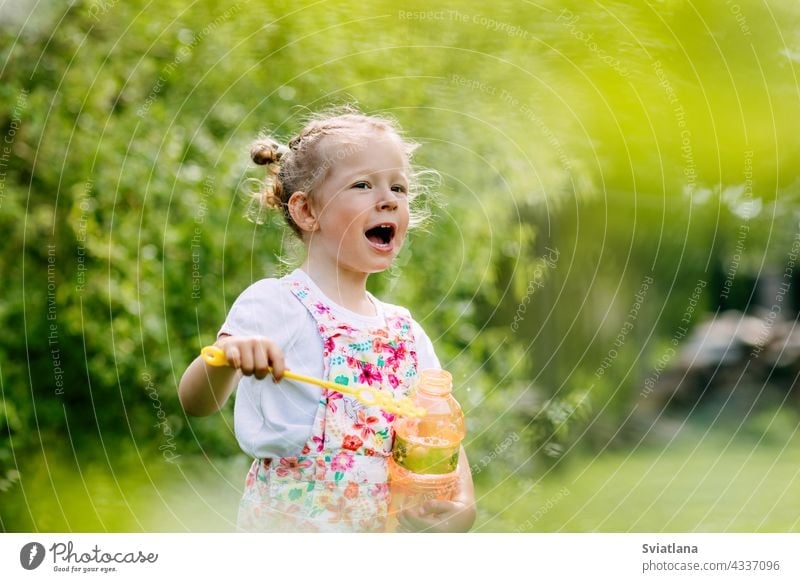Charming baby girl with soap bubbles in the park or garden little joy childhood green fun portrait blow beautiful kid summer play cute nature funny blowing game