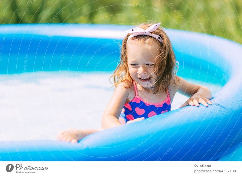 Portrait of a beautiful baby girl in the pool in the garden water playing fun childhood summer kid swimming joy swimsuit family funny little vacation sun