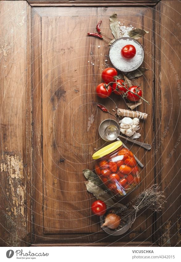 Tomatoes preserving.  Jar with fermented tomatoes on wooden table background with ingredients. Top view jar top view nobody natural traditional pickled