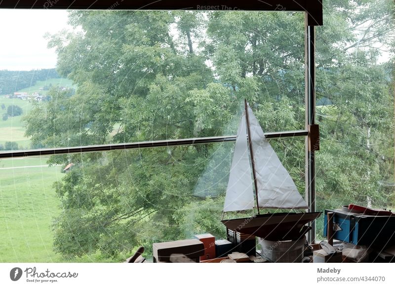 Beautiful wooden model of a sailing yacht with white sails on the workbench in a converted old barn with panorama window on a farm in Rudersau near Rottenbuch in the district of Weilheim-Schongau in Upper Bavaria