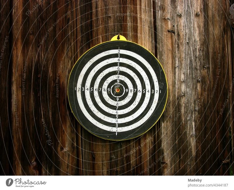 Old round target for the dart game with arrows on the brown wood of an old barn in Rudersau near Rottenbuch in the district Weilheim-Schongau in Upper Bavaria
