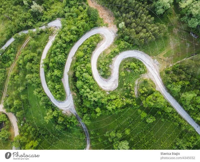 Drone view of beautiful serpentine road leading through mountain landscape in summer.  Aerial photography of a road shot using a drone.  Damaged road surface