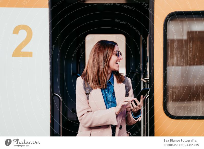 young backpacker caucasian woman at train station using mobile phone. Travel concept travel happy technology daytime Porto platform arrival baggage beautiful