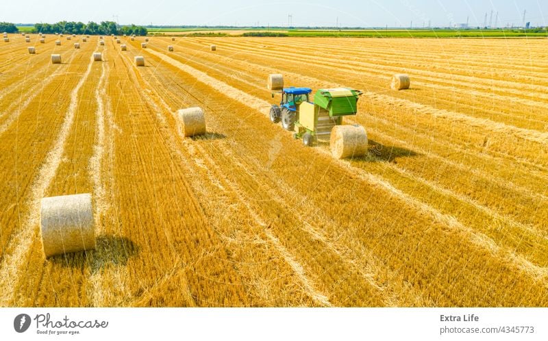 Aerial view of tractor tow trailed bale machine to collect straw from harvested field Above Agricultural Agriculture Arable Bale Baler Baling Cereal Compact