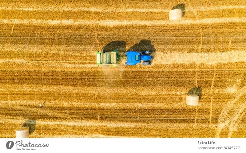 Aerial view of tractor tow trailed bale machine to collect straw from harvested field Above Agricultural Agriculture Arable Bale Baler Baling Cereal Compact