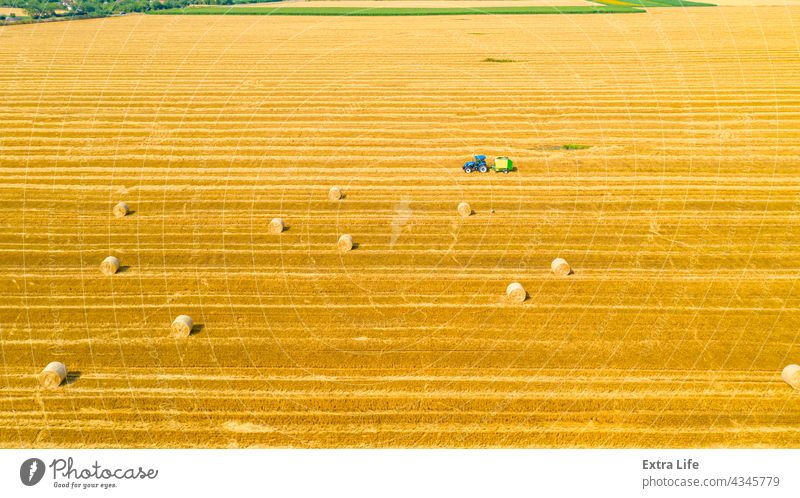 Aerial view of tractor tow trailed bale machine to collect straw from harvested field Above Agricultural Agriculture Arable Bale Baler Baling Cereal Compact