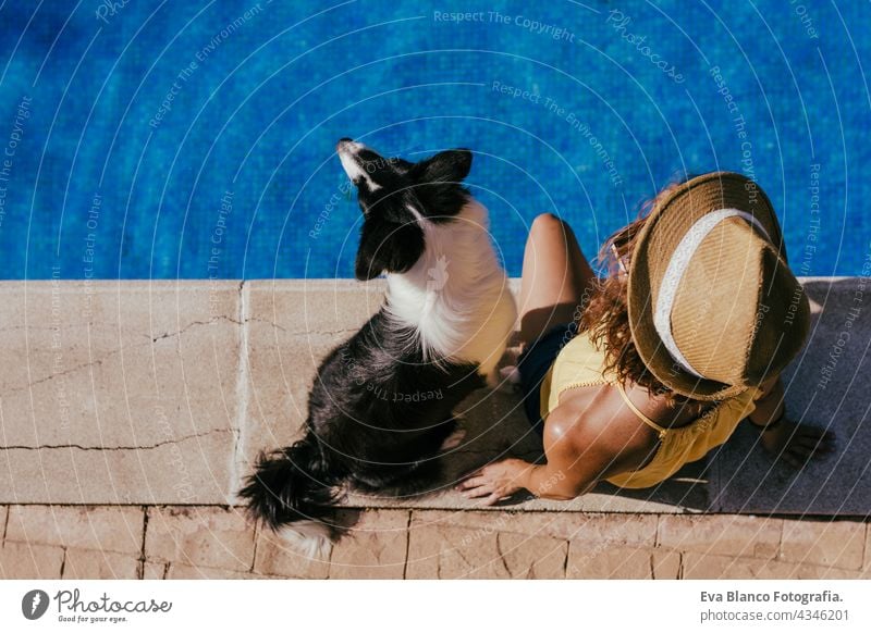 top view of young caucasian woman sitting by pool side with cute border collie dog. Summer time, vacation and lifestyle swimming pool summer together love owner