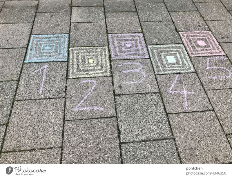 1,2,3,4,5 is written on the floor with sidewalk chalk. Box hopping, children's game, hopping game. street chalk Infancy square hopping Hop Children's game Joy