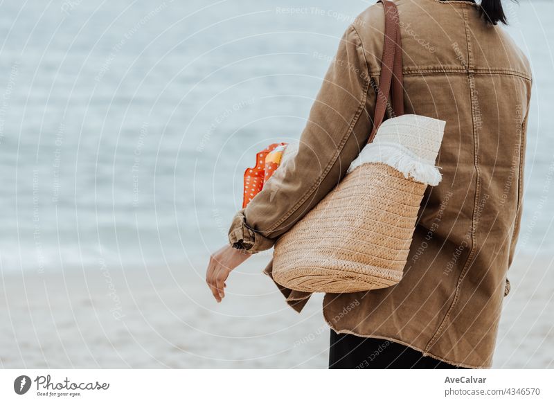 Close up of a woman on the beach holding a beach bag during a bright day, copy space, vacation and freedom concept person rear long hair tropical back brunette