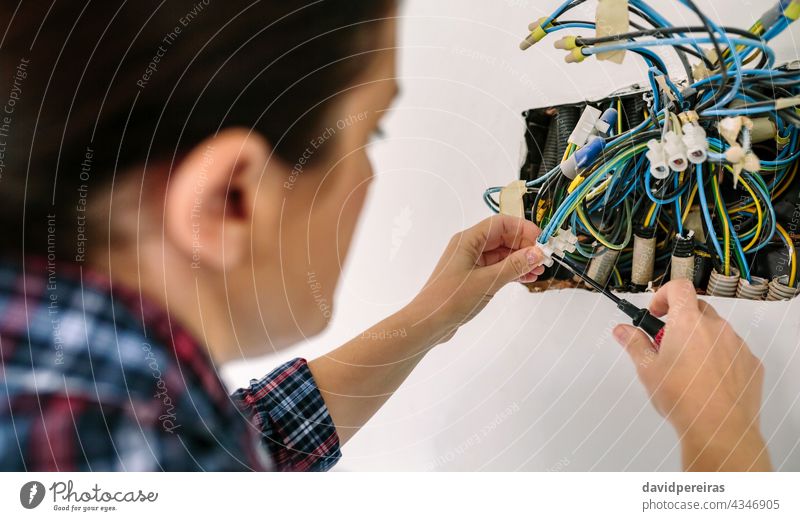 Electrician working on the electrical installation of a house electrical technician unrecognizable woman corrugated pipe screwdriver repairing closeup