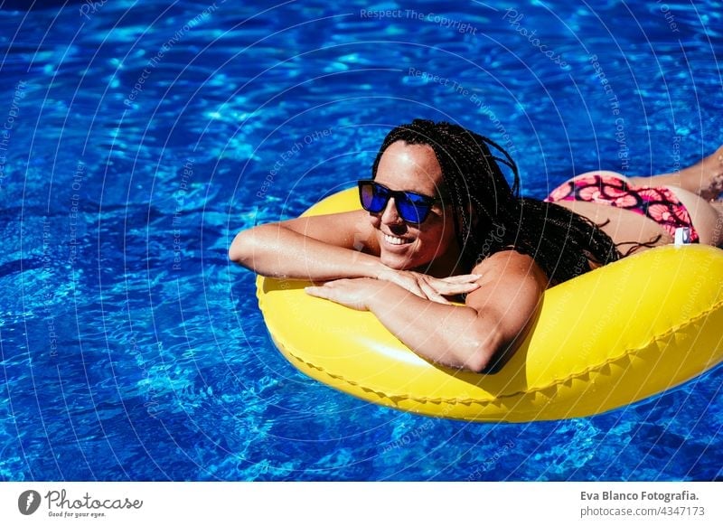 top view of happy caucasian woman relaxing on yellow donuts inflatable at swimming pool. Summer time, vacation and lifestyle floating summer sunglasses fun