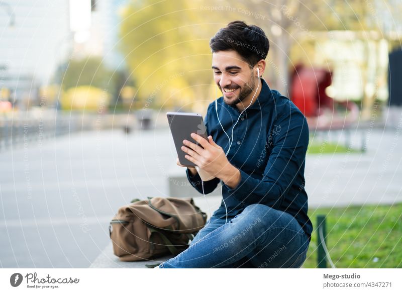 Young man having a video call on digital tablet outdoors. young technology mobile working social network touchscreen outside online concept display wireless