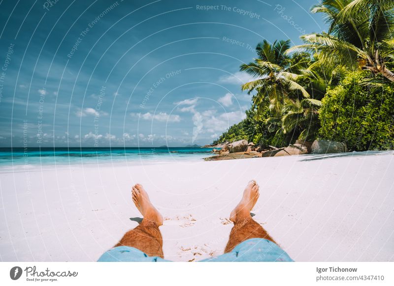 man resting on the white sand beach with beautiful palm trees seychelles travel vacation tropical sun summer relaxation outdoor ocean leg island coast tourism