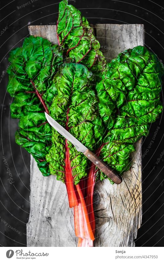 Fresh raw chard leaves and a knife on a wooden cutting board Mangold Raw Knives Rustic Chopping board Wood Vegetable Vegetarian diet Ingredients Green Healthy