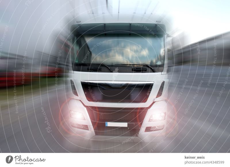 A truck drives towards the viewer with blinding headlights Truck lorry lorries Logistics Transport logistics Shipping Vehicle Delivery cargo Street Industry