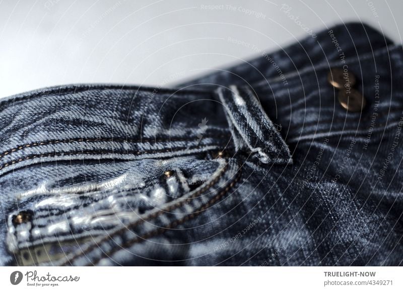 Almost new, cult and stylish: detail shot of a pair of washed out and torn blue jeans with trouser pocket, belt loop and metal buttons Bluejeans style Fashion