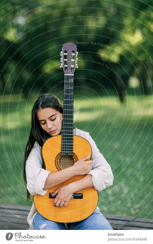 An attractive girl with a guitar in the park. The concept of creative hobbies and professionals. The girl is a musician portrait guitarist lifestyle female