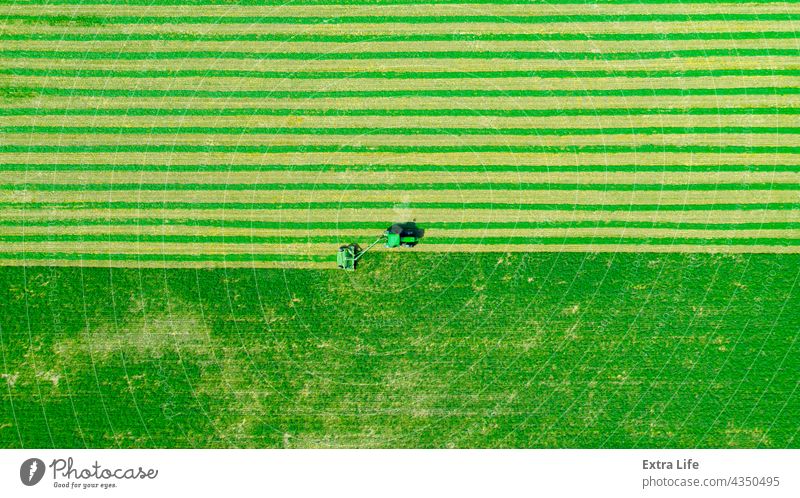Aerial view of tractor as tow lawn mower machinery behind Above Agriculture Alfalfa Attached Clipper Clover Crop Cut Cutter Drag Farming Farmland Fast Field
