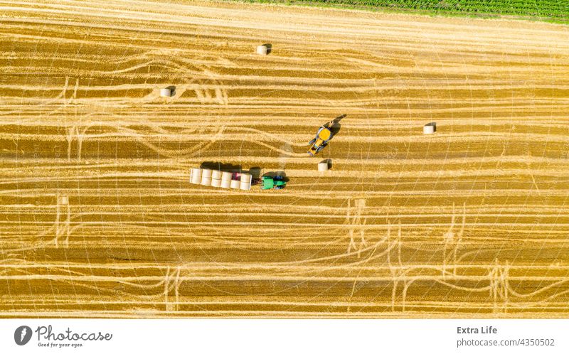 Above view of agricultural field, collecting round bales of straw Aerial Agricultural Agriculture Bale Cargo Carry Cereal Covered Enveloped Excavator Farming