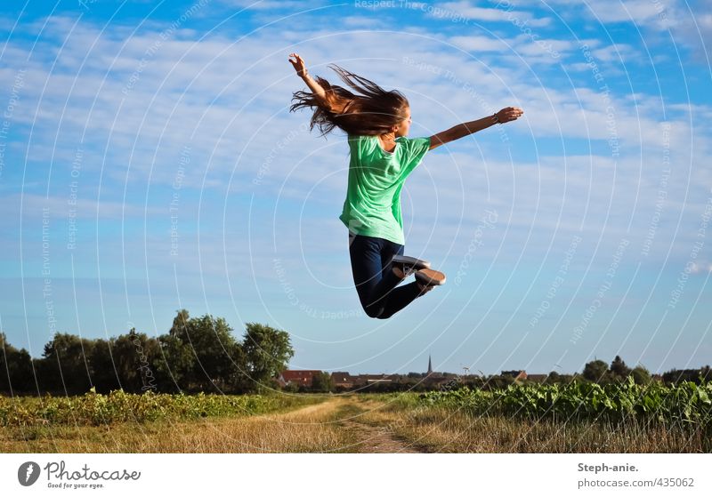 up Feminine Young woman Youth (Young adults) 1 Human being Earth Sky Clouds Summer Beautiful weather Grass Field T-shirt Jeans Long-haired To enjoy Jump Free