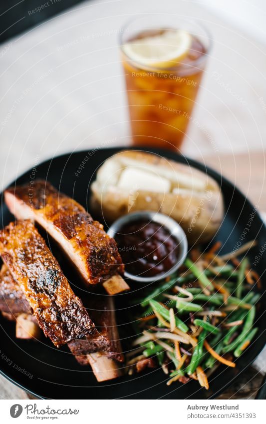 Ribs dinner meal with fancy green beans and potato on a farmhouse country linen tablecloth american background baked baked potato barbecue barbecued barbeque