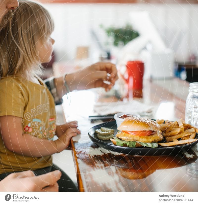 father and daughter eating a cheeseburger meal with fries in an american diner background barbecue bbq beef big blonde bread bun cheddar daddy date delicious