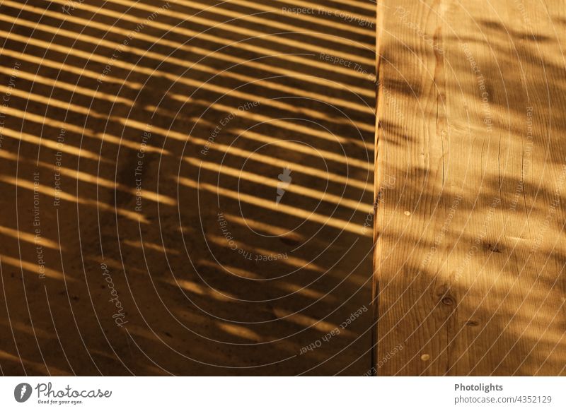 Shadow of a grid in front of wooden bench Grating Wooden board Wooden bench Warmth Light Sun Sunlight Rich in contrast Contrast Shadow play Colour photo