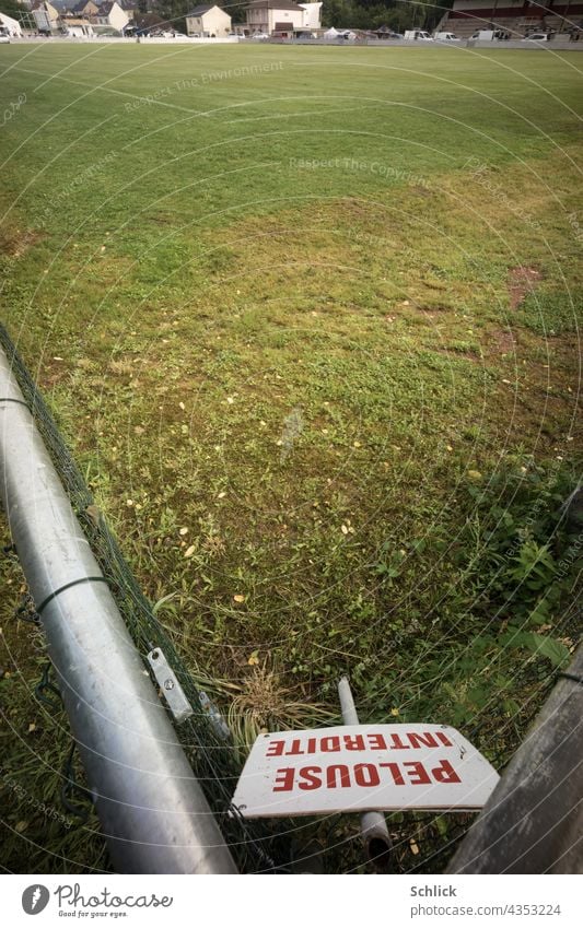 Sign with red inscription PELOUSE INTERDITE Do not enter lawn stands in the corner of a football field Foot ball Football pitch sign Lawn No trespassing French