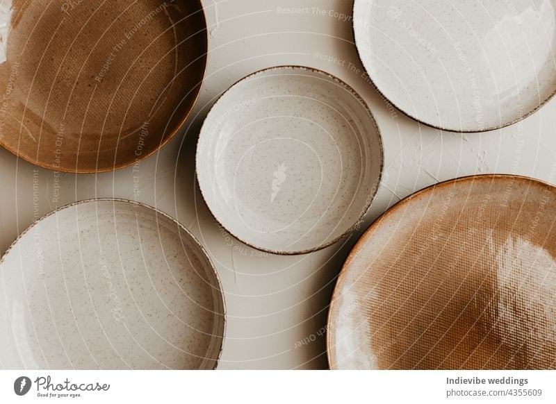 Five different size plate on beige background. Textured grainy pattern on the plates. Flat lay, top view. Brown and natural color plates. art bowl bowls