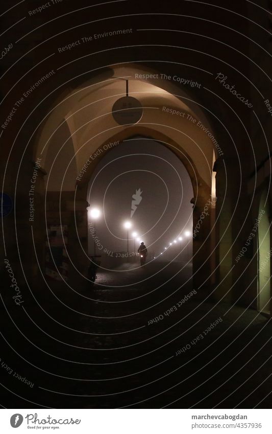 Foggy street light in night. Man silhouette riding the bike on the Stone Bridge in the city center fog photography outdoors road illuminated travel dusk mystery