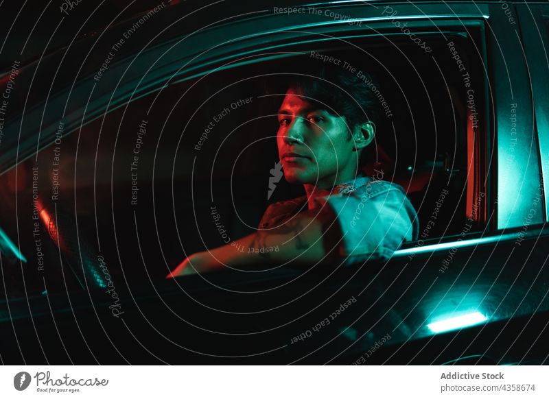 Latin man in car with color lights night latin young hispanic neon colorful smoke vaping dark driver city modern traffic people black transport vehicle scene