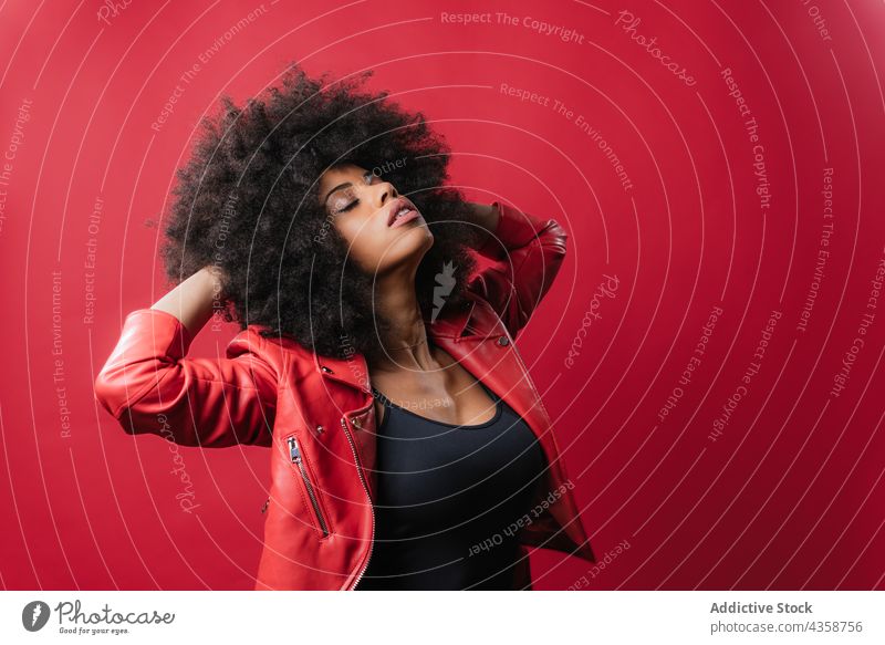 Rebellious black woman shouting and touching curly hair on red background rebel naughty scream style loud afro expressive touch hair female ethnic