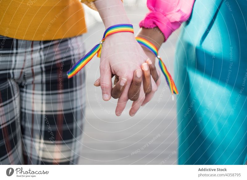 Crop multiracial lesbian couple with rainbow bracelets holding hands women lgbt equal homosexual pride female multiethnic diverse black african american right