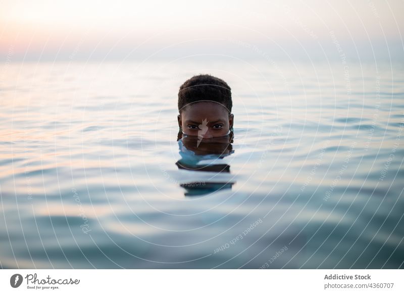Black woman with short hair and half face in sea water sunset ripple sundown evening summer female ethnic black african american tranquil relax carefree holiday