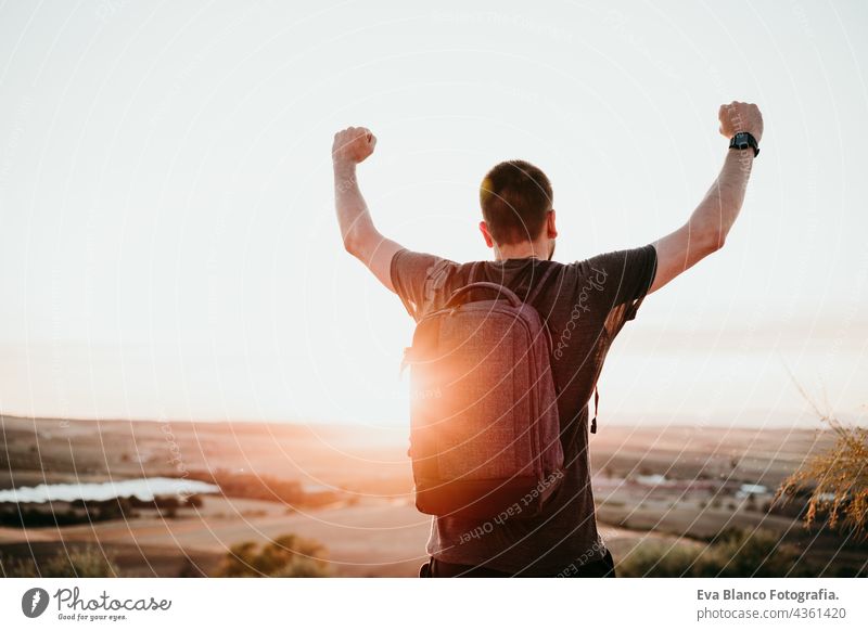 successful man with arms raised standing on top of mountain during sunset. Hiking and nature backpacker hiking adventure travel wanderlust dawn flare