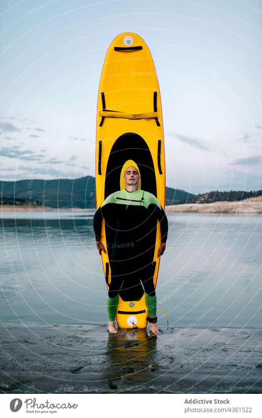 Surfer with paddleboard on seashore surfer man beach sup board wetsuit surfboard ocean male sport water summer surfing coast seaside activity calm serene